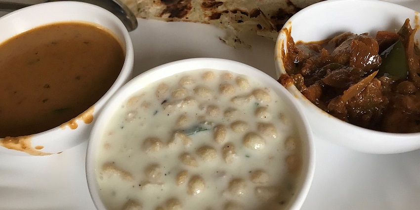 A north Indian veg thali consisting of butter naan, dal tadka, and boondi raita.