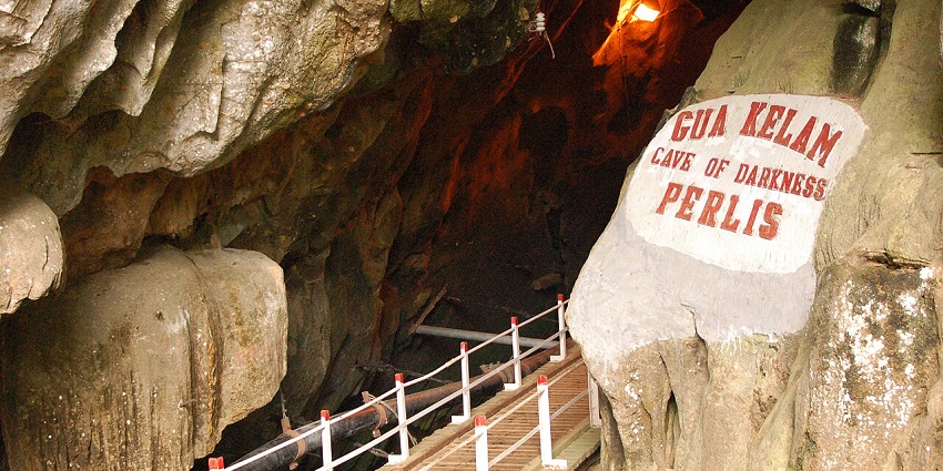 Entrance of Gua Kelam, Cave of Darkness in Perlis, with a wooden walkway and rock walls, one of the top caves in Malaysia.
