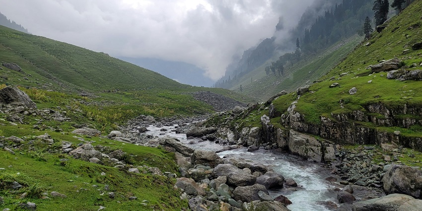 A river flows gently through the scenic Gulmarg Valley in Kashmir.