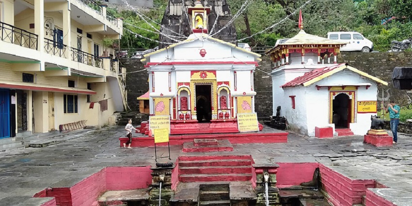 Temple complex with red-white buildings and pool, near Guptkashi caves in Uttarakhand.
