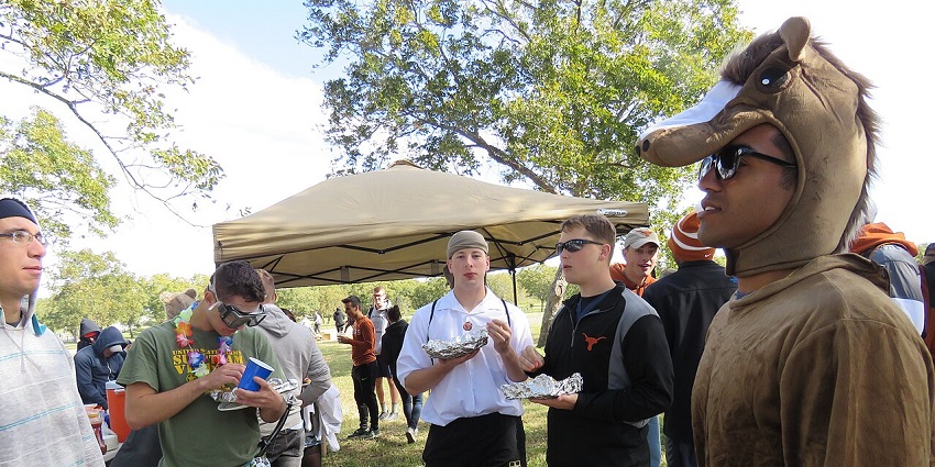 A guy dressed as an animal and wearing sunglasses enjoys Halloween games with his friends.