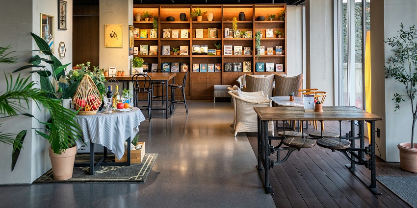 Hard Rock Cafe interior with wooden tables, chairs, and wall-mounted bookshelf.
