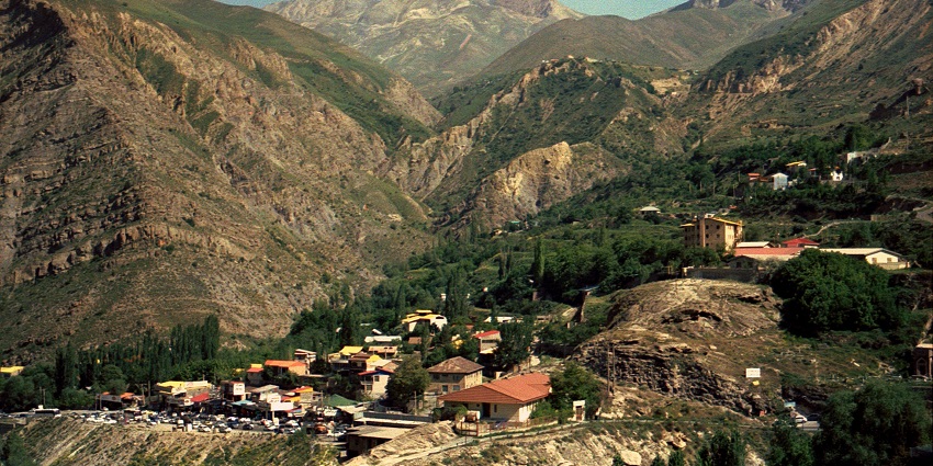A panoramic view of barren, serrated mountains with a vivid blue sky and clouds.

