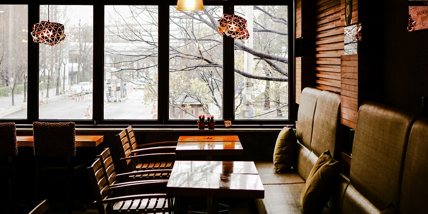 Brown wooden table with chairs under dim lighting at Hi Spirits restaurant.
