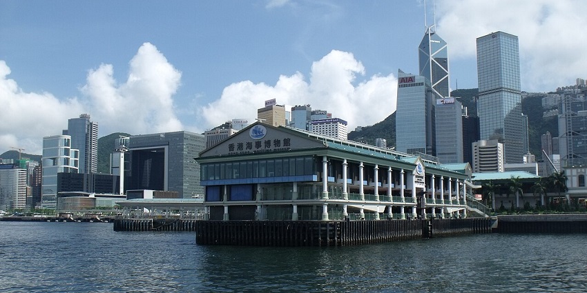 Hong Kong Maritime Museum on Victoria Harbour waterfront with city skyscrapers behind.