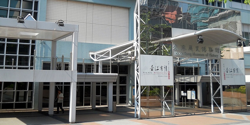 Exterior view of the Hong Kong Museum of History with trees and city buildings behind.