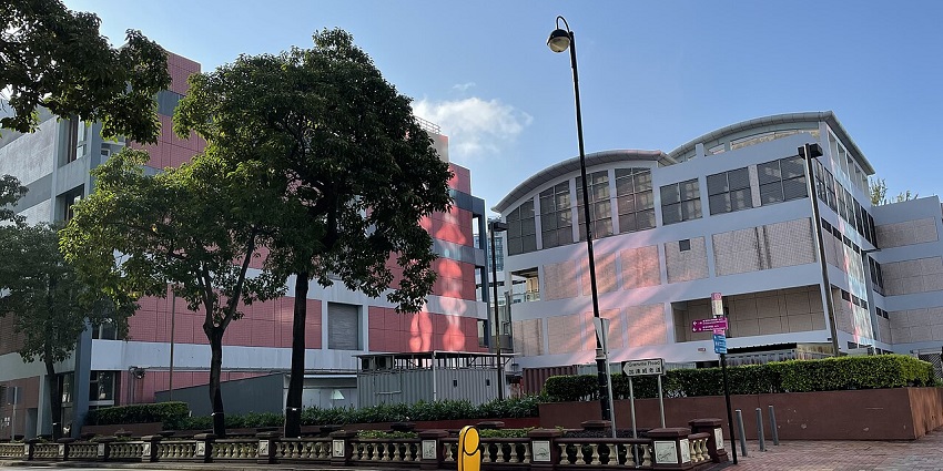 Hong Kong Science Museum exterior with curved roof, red-white walls, and trees outside.