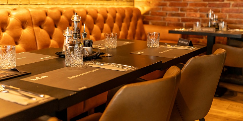 Restaurant table with crystal glasses, leather seating, and exposed brick wall decor, one of the top restaurants in Namchi.