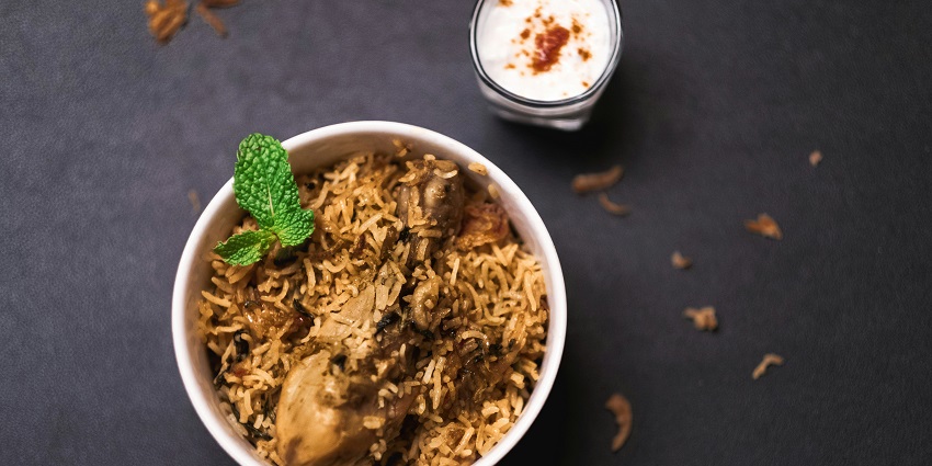 Chicken biryani served with raita and garnishes on a restaurant plate at India Gate.
