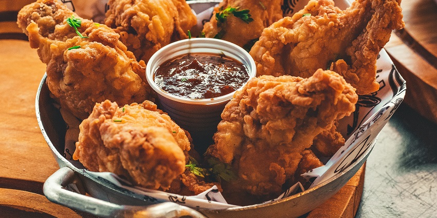 Plate of fried chicken served at a restaurant table with garnish and dipping sauce.
