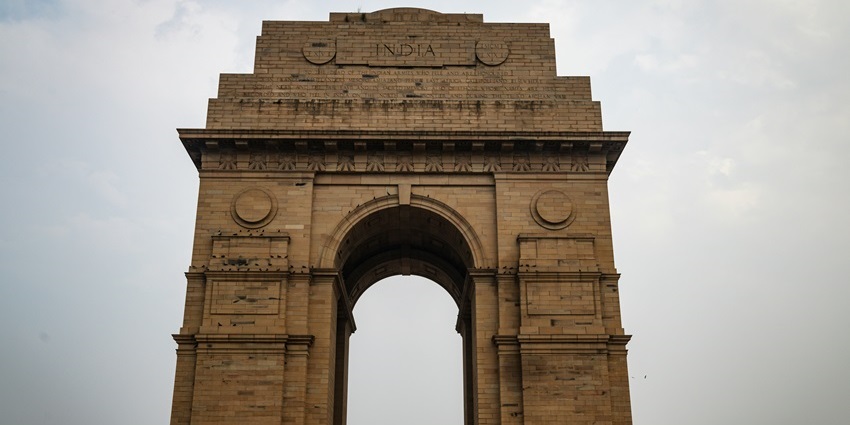 India Gate stands tall against a clear sky in Delhi during the daytime.