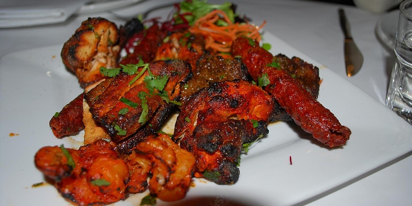 A platter of tandoori meats, chicken, and seekh kebabs, garnished with fresh cilantro, in one of the Indian restaurants in Kuala Lumpur.
