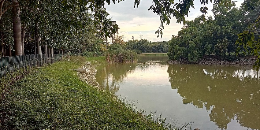 Scenic lake with trees and a walking path inside Jayaprakash Narayan Park, one of the beautiful parks in Karnataka.
