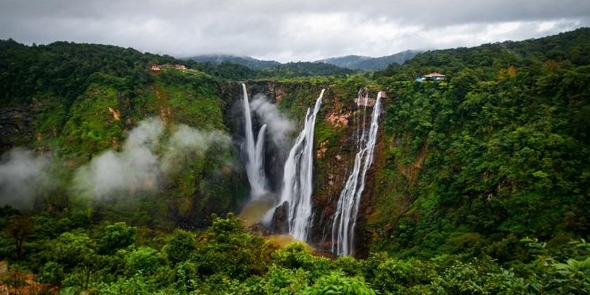 A majestic waterfall cascading down rocky cliffs surrounded by dense forest.