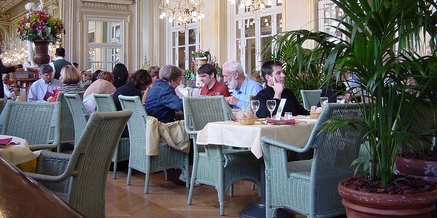 A crowded, elegant dining room with a high ceiling, ornate decor, and many people eating, one of the vegetarian restaurants in Singapore Little India.
