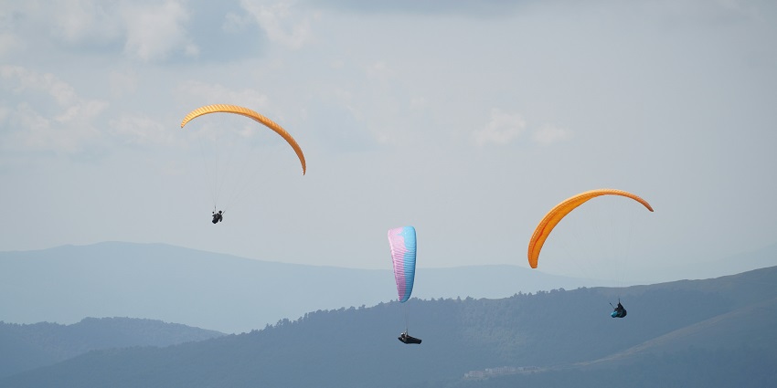 Paragliding in Karnataka at Karwar with three paragliders soaring over the scenic coastline.