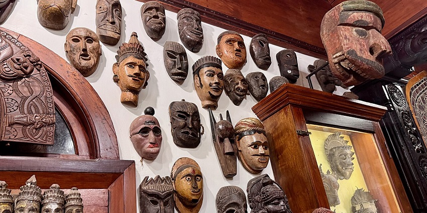 Kerala Folklore Museum display wall with traditional wooden masks and carved artefacts, one of the art galleries in Kerala.
