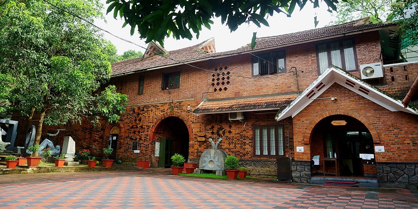 Kerala Lalithakala Akademi Art Gallery building with red brick walls and greenery outside.
