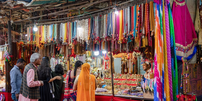 Market in Pushkar Mela with a jewellery shop, hanging jewellery and people visiting the shop.