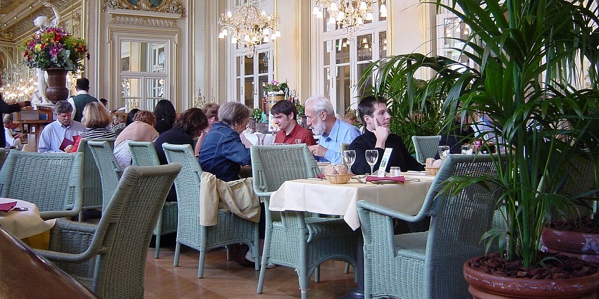 A crowded, elegant dining room with a high ceiling, ornate decor, and many people eating, one of the best Indian restaurants in Singapore, Little India.

