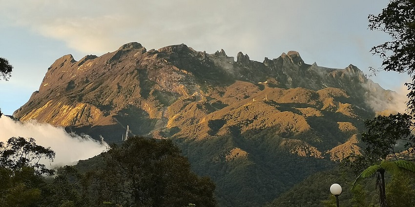 Kinabalu National Park with Mount Kinabalu at a distance under sunlight and clear skies, one of the best parks in Malaysia.
