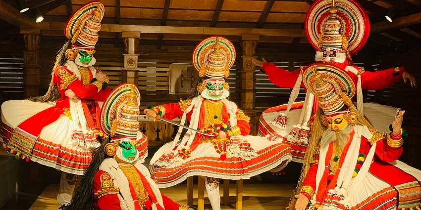 People wearing multicolored costumes are dancing during a vibrant festival in Kochi.
