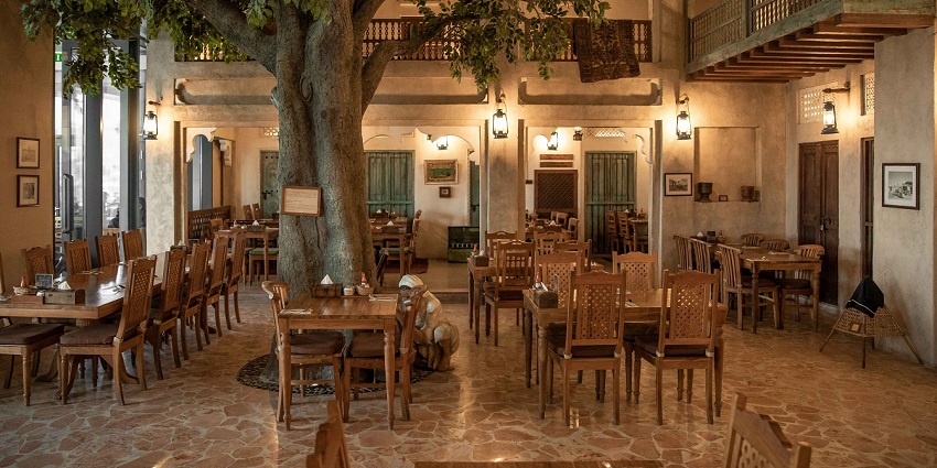 A rustic restaurant with many wooden tables and chairs, and a large tree in the centre, one of the best Indian restaurants in Singapore.
