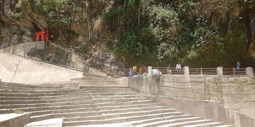 A long, concrete staircase leads up to a small building and a narrow path along a green, rocky hillside.

