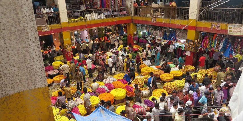 Crowded flower market in Karnataka with vibrant marigolds, vendors, and shoppers enjoying shopping in Karnataka.
