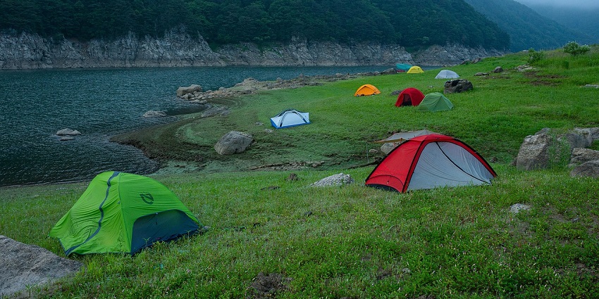 Camping tents set on a grassy hillside surrounded by misty peaks at Kudremukh trek.