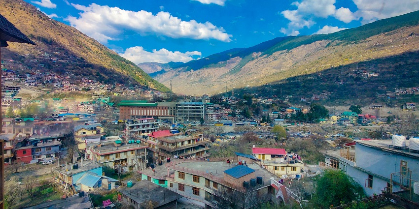 Snow-covered Himalayan peaks seen from Kullu Valley, with forests in the foreground.
