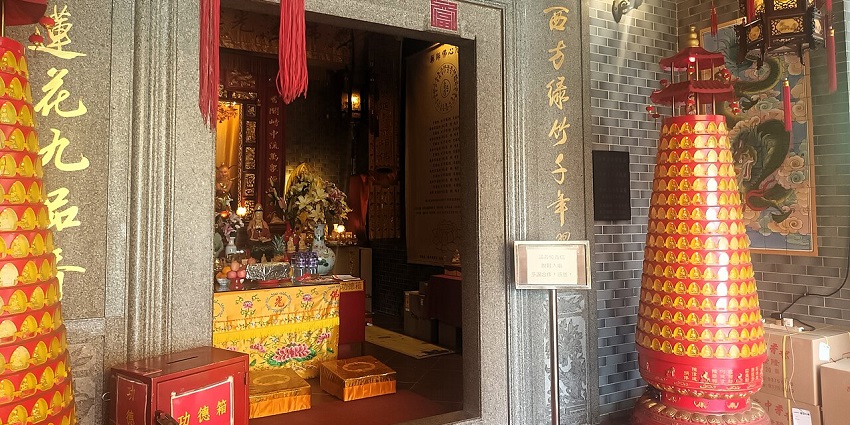 Kwun Yam Temple in Hong Kong with multiple signs on the wall and decorations.
