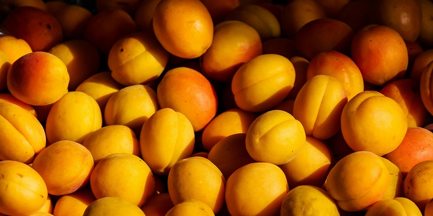 Pile of fresh ripe peaches displayed at a market stall.
