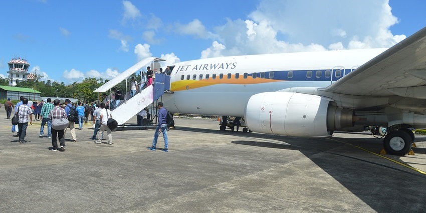 Passengers boarding a Jet Airways aircraft at Lengpui Airport under clear skies and sunshine.