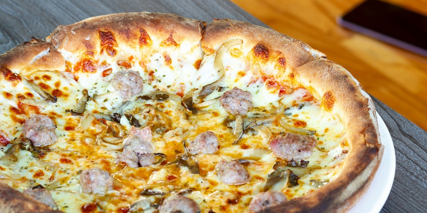 Wood-fired pizza served at Lhasa Newar Kitchen & Bar on a wooden platter.

