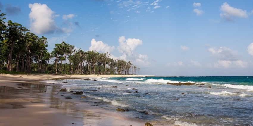 Scenic coast of Little Andaman Island with blue waters, sandy shores, and lush greenery.