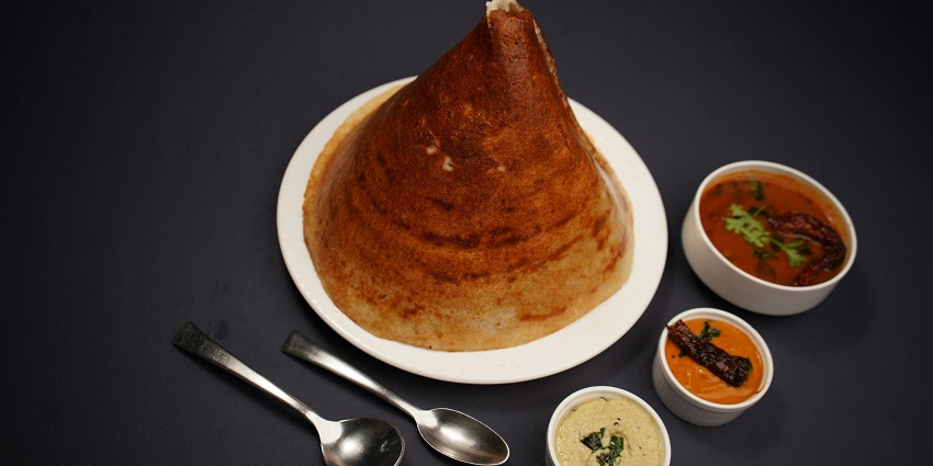 Masala dosa served on a plate with chutneys and sambar at MTR Singapore restaurant.
