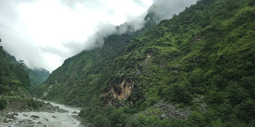The Teesta River flows through rocks surrounded by green mountains, one of the popular hill stations in Sikkim.

