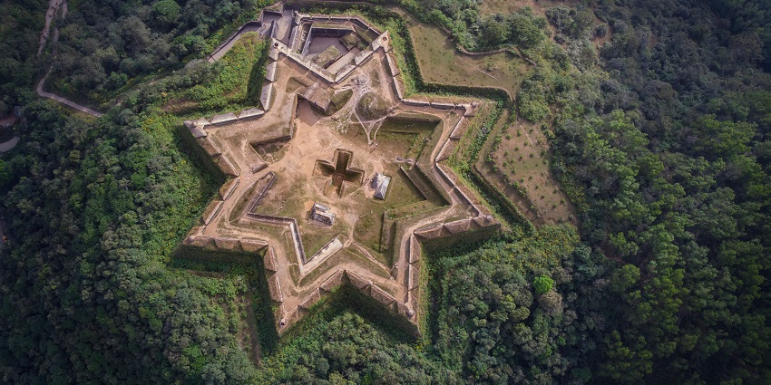 Aerial view of star-shaped Manjarabad Fort surrounded by lush green landscape.