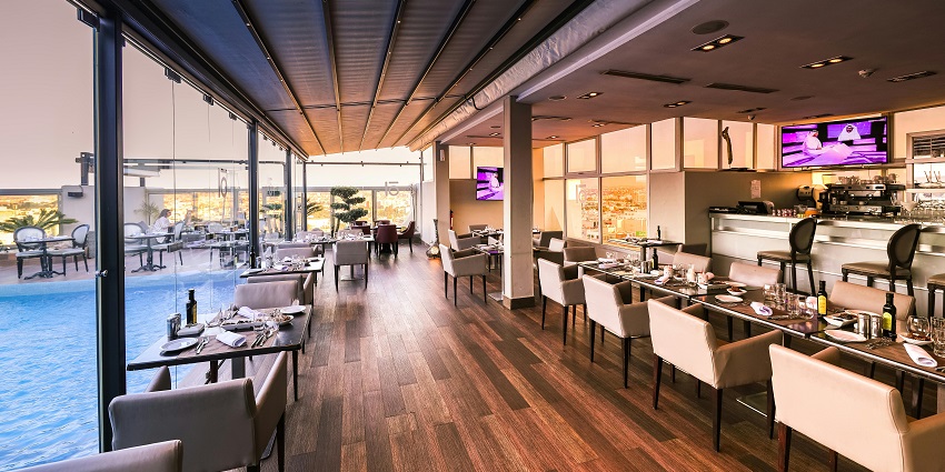 Elegant restaurant with poolside view, glass walls, and neatly arranged dining tables.