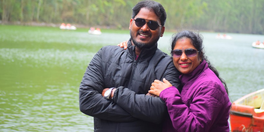 An enchanting portrait of a couple with clear backwaters in the backdrop during the day.