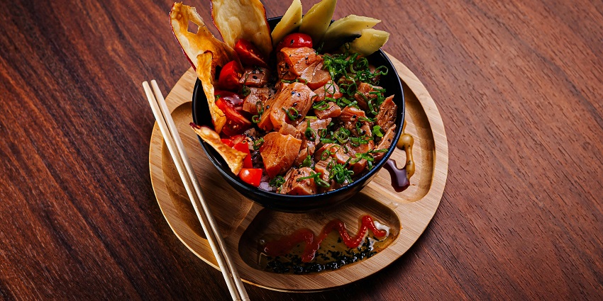 Bowl of diced meat with herbs, tomatoes, and crisps, served on a wooden platter, among the top restaurants in Kurseong.