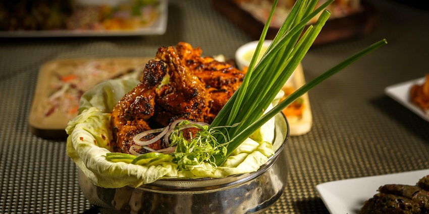 Grilled chicken drumsticks served in a lettuce-lined bowl with onions and greens, one of the best restaurants in Kurseong.