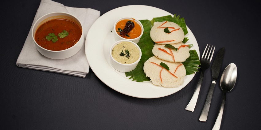 Sambhar idli with chutney served on a white plate at Murugan Idli Shop.
