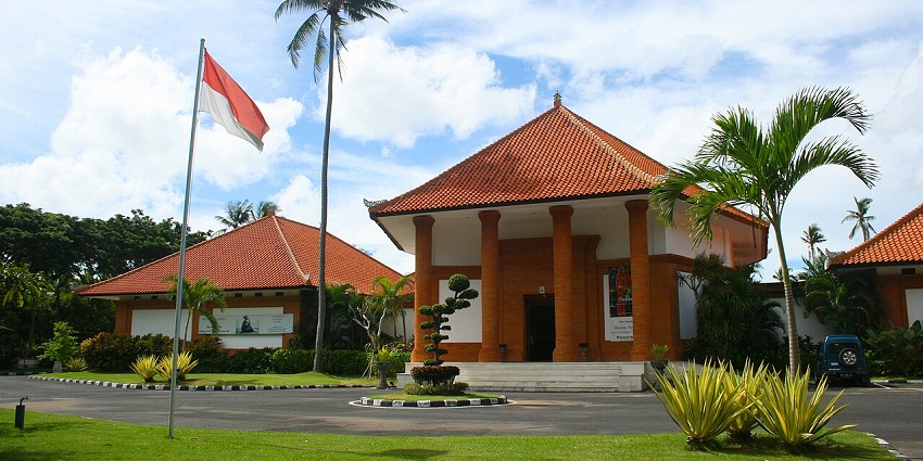 Museum Pasifika in Nusa Dua, Bali, with a red-tiled roof, palm trees, and Indonesian flag.
