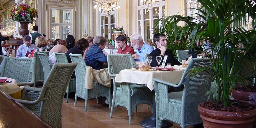A crowded, elegant dining room with a high ceiling, ornate decor, and many people eating, one of the best Indian restaurants in Singapore.
