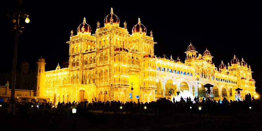 People gathered in front of the bright illuminated Mysuru Palace during Dussehra celebration in India.