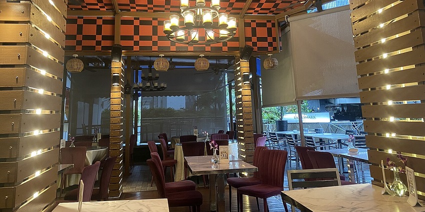 Cosy restaurant interior of Singapore, with red chairs, wood accents, and a checkered ceiling, one of the best restaurants in Singapore.
