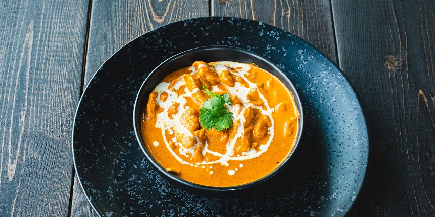 Close-up of a bowl of butter chicken curry garnished with fresh coriander leaves, one of the indian restaurants in Cappadocia Turkey.
