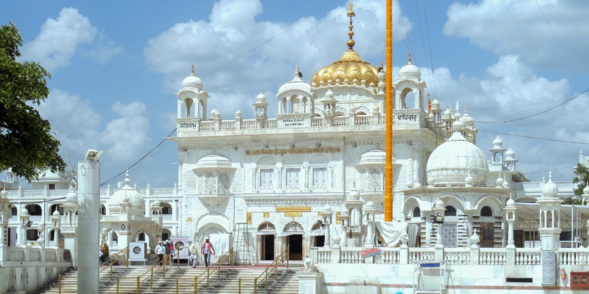 Hazur Sahib gurdwara in Nanded, Maharashtra, has white walls, golden domes and a tall Nishan Sahib.